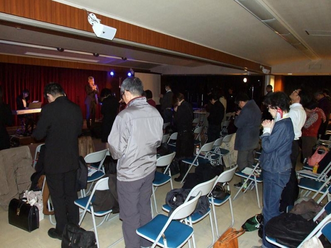 万代氏と心を新しくされることを願う参加者が共に祈りを捧げている。２０１２年１２月２０日、東京都千代田区で。