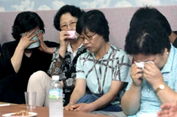 拉致事件に関するニュースを見ながら悲しむ人質の家族ら＝２７日、韓国・城南（ソンナム）市で
