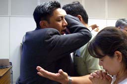 希望者一人ひとりに手を置き、神の働き人となるよう祝福を祈るレイモンド・ムーイ氏＝６月２０日、東京・中野区で