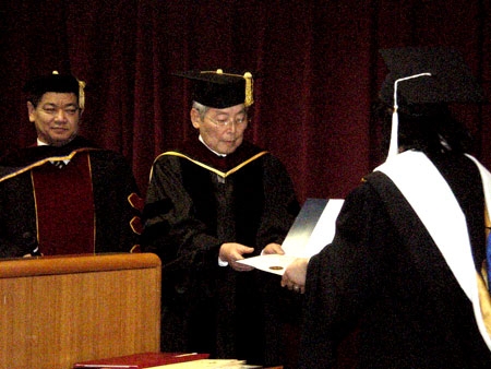 学位記（証書）を卒業生に手渡す佐藤陽二総長（写真中央）と佐藤順学長（同左）