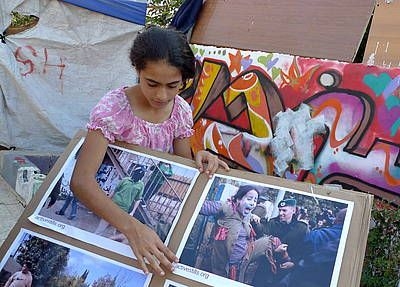 １２歳の女の子が強制移住させられた家族の写真を掲げている（写真提供：ＷＣＣ）。 